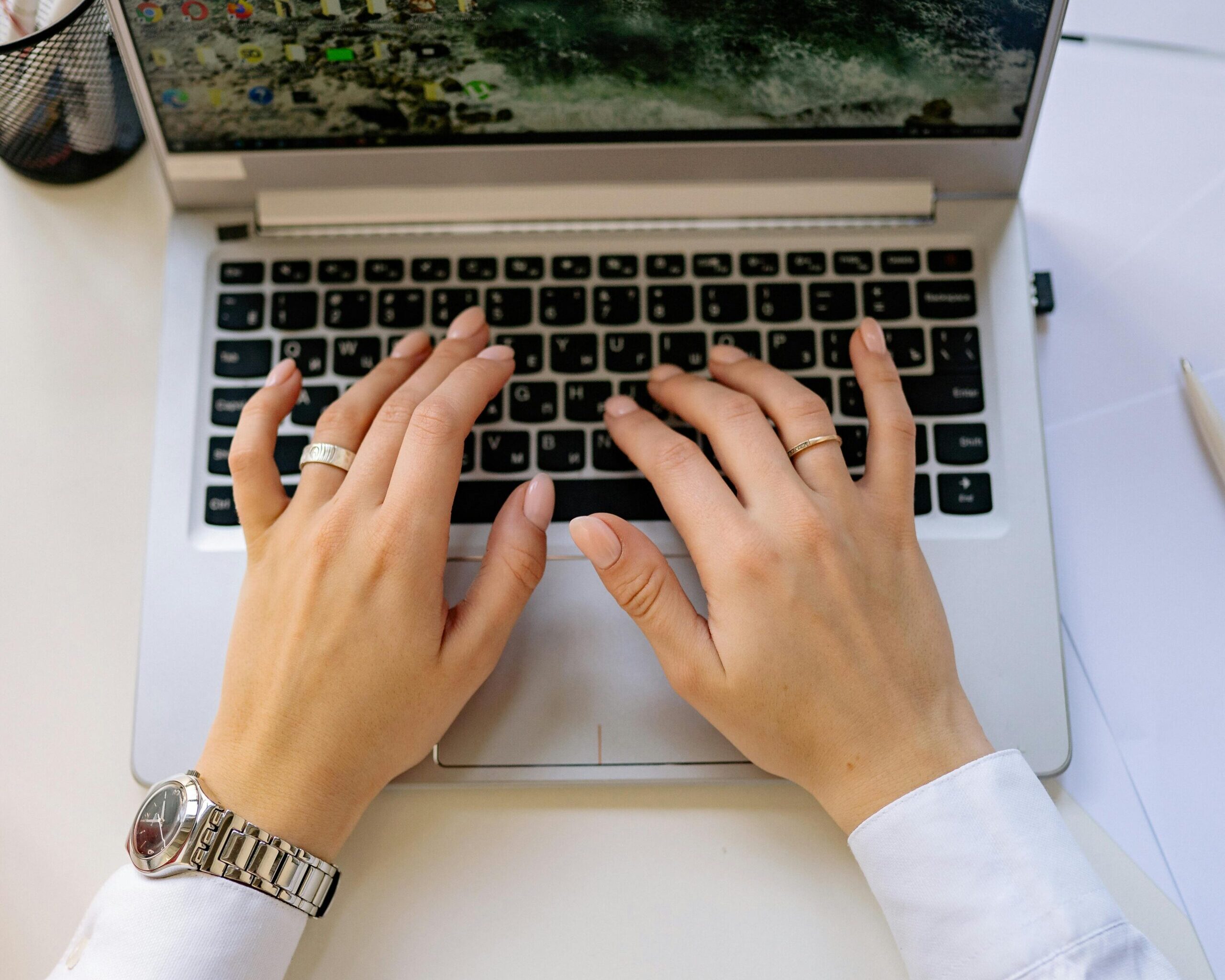 Hands typing on a sleek laptop keyboard in a bright, modern workspace. Ideal for business concepts.