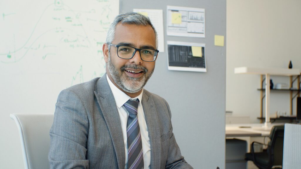 Confident senior businessman in suit and tie, smiling in modern office.