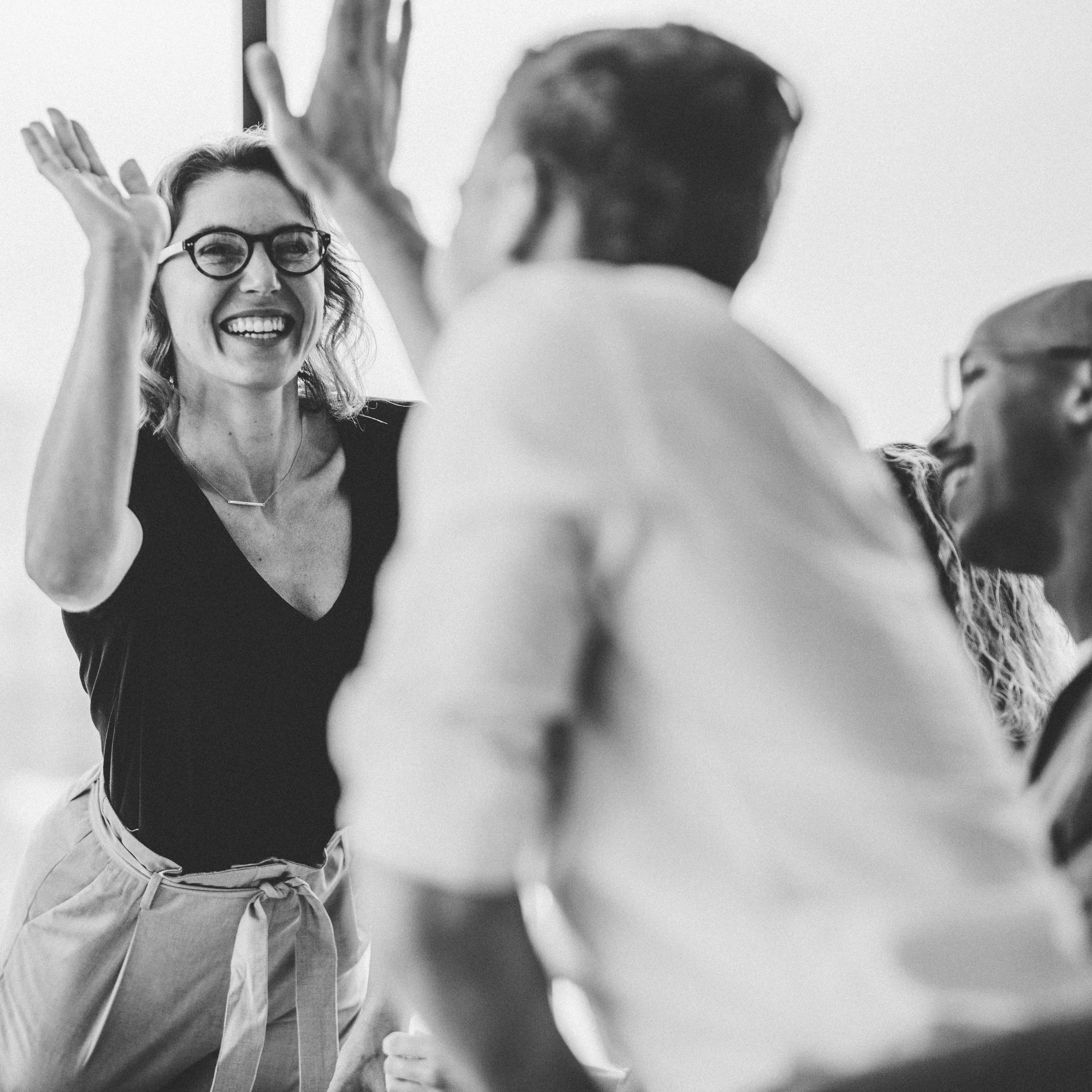 Businesswoman,Giving,A,High,Five,To,Male,Colleague,In,Meeting. Businesswoman giving a high five to male colleague in meeting. Business professionals high five during a meeting in boardroom.