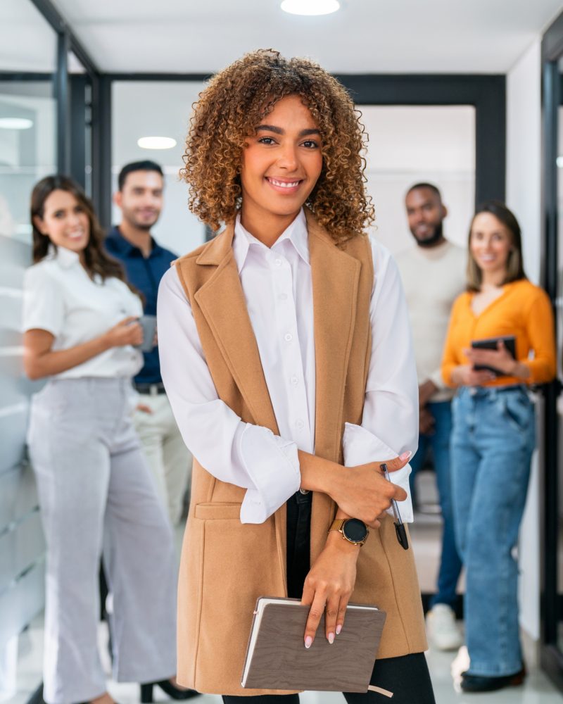 Businesswoman leading a business team at the office and smiling Successful African American businesswoman leading a business team at the office and looking at the camera smiling