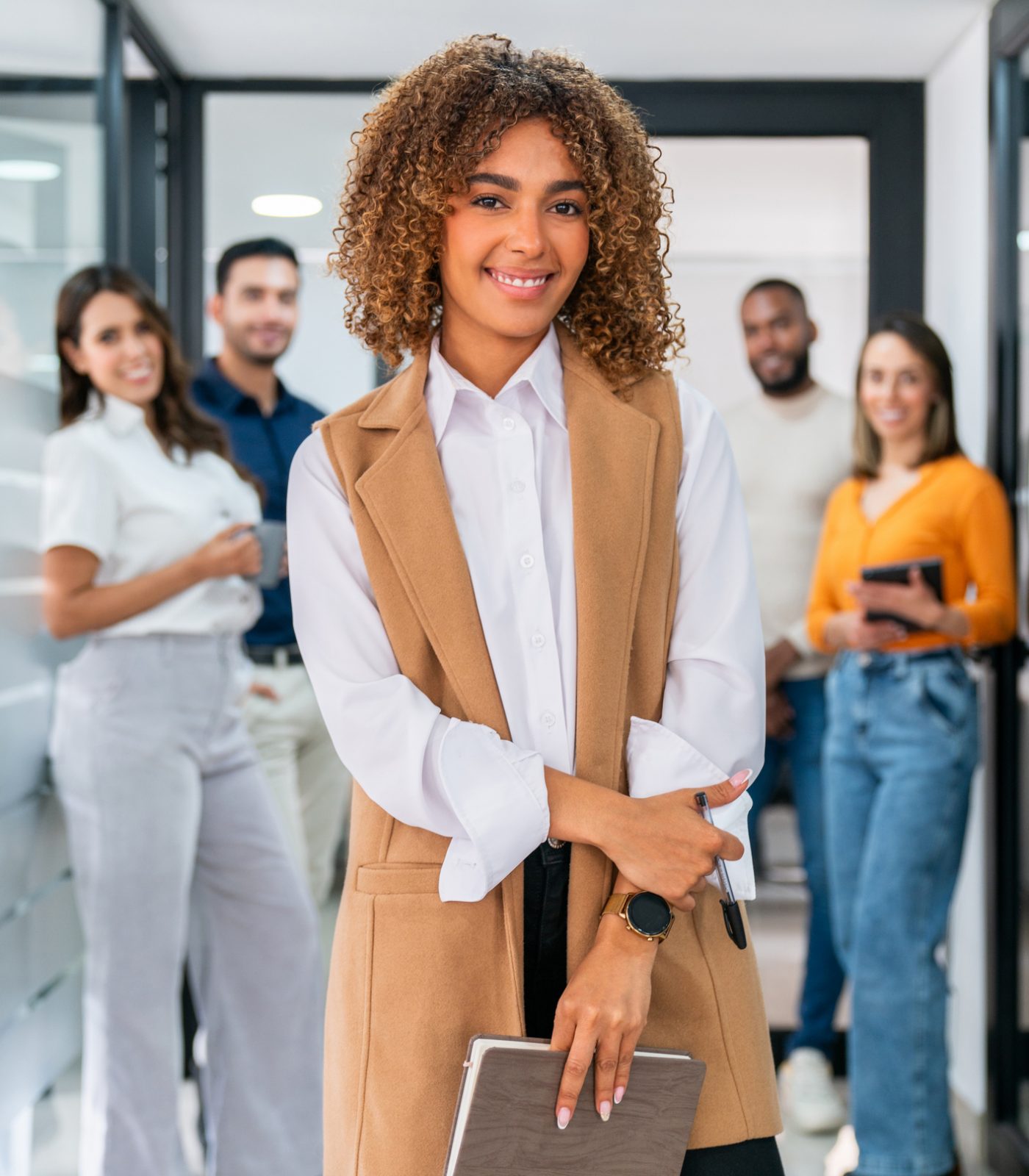 Businesswoman leading a business team at the office and smiling Successful African American businesswoman leading a business team at the office and looking at the camera smiling